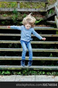 Happy blond child jumping wooden stairs . Happy blond child with jeans and denim shirt jumping wooden stairs