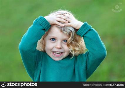 Happy blond child with his hands on the head in a park