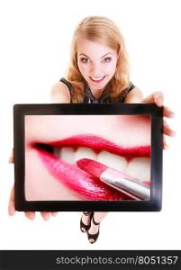 Happy blond girl showing ipad with photo of female lips and red pink lipstick. Modern young woman holding tablet touchpad recommending makeup. Isolated. Technology and beauty. Studio shot.