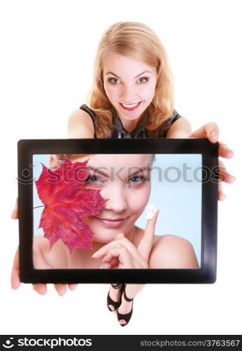 Happy blond girl showing ipad with photo of woman with red leaf and moisturizing cream. Modern young businesswoman holding tablet touchpad recommending care of dry skin. Isolated. Technology and beauty.
