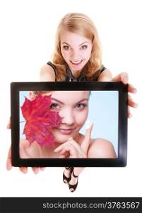 Happy blond girl showing ipad with photo of woman with red leaf and moisturizing cream. Modern young businesswoman holding tablet touchpad recommending care of dry skin. Isolated. Technology and beauty.