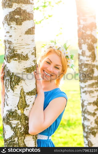 Happy blonde embracing birch trunk in the park