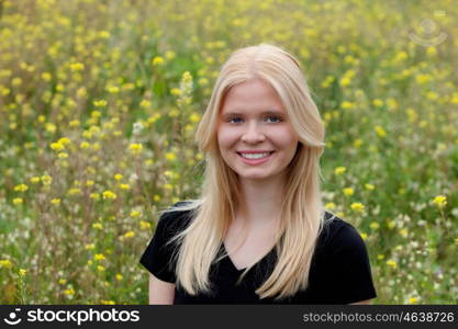 Happy blonde girl in the field surrounded by flowers