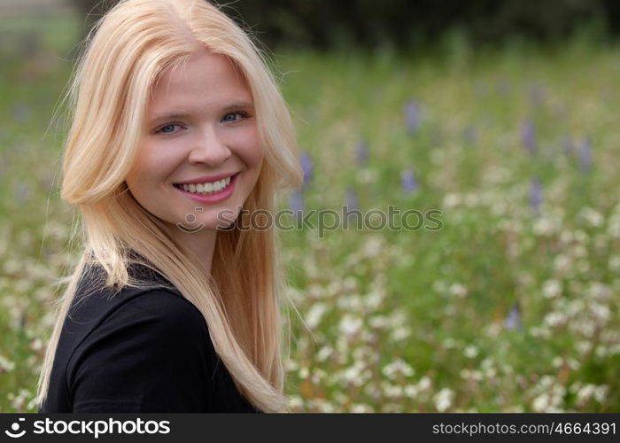 Happy blonde girl in the field surrounded by flowers