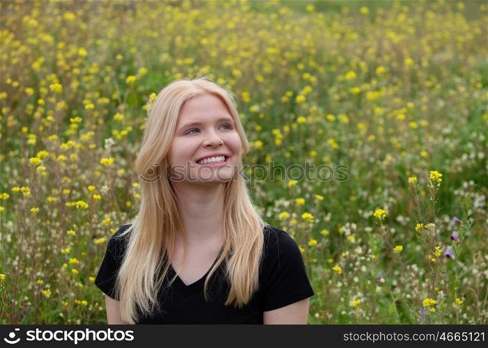 Happy blonde girl in the field surrounded by flowers