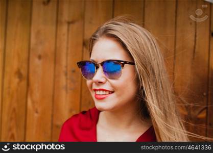 Happy blonde girl with red clothes and lips on a wooden background