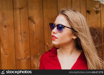 Happy blonde girl with red clothes and lips on a wooden background