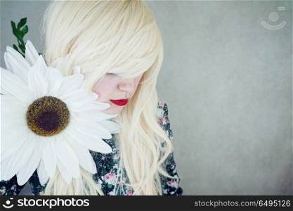 Happy blonde woman posing near a huge flower