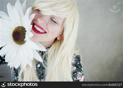 Happy blonde woman posing near a huge flower