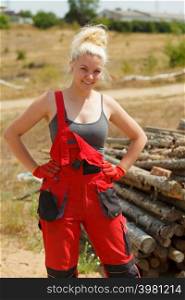 Happy blonde woman wearing dungarees about to do some work on construction site. Women power, gender equality, industrial worker.. Woman in dungarees working on construction site