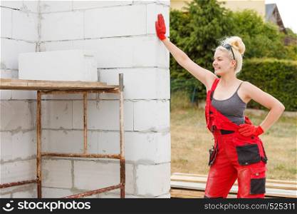 Happy blonde woman wearing dungarees about to do some work on construction site. Women power, gender equality, industrial worker.. Woman in dungarees working on construction site
