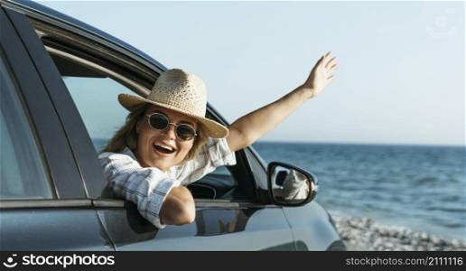 happy blonde woman with hat looking out car window