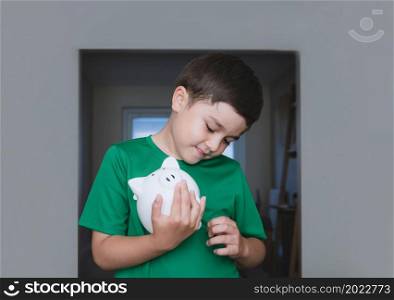 Happy boy holding piggy bank with smiling face. Portrait of a cheerful child showing money saving box.School kid Learning financial responsibility and planning about saving for future concept