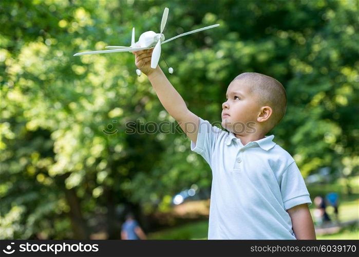 happy boy play and throw airplane toy in park
