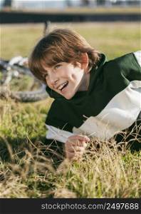 happy boy relaxing grass while riding his bike