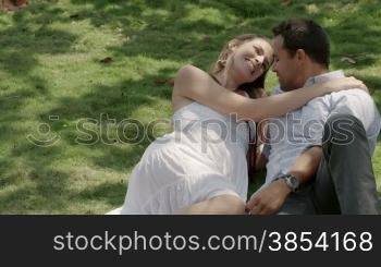 Happy boyfriend and girlfriend in love, laying on grass in park and hugging during date