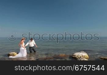 happy bride and groom are laughing by the sea