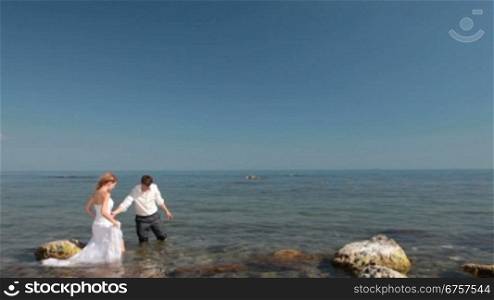 happy bride and groom are laughing by the sea