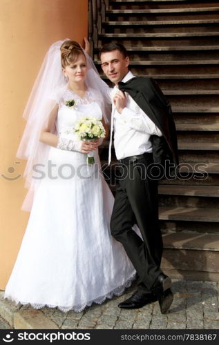 Happy bride and groom near wooden stairs