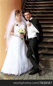 Happy bride and groom near wooden stairs