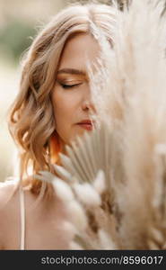 happy bride girl in a white light dress with a bouquet of dried flowers on a forest path