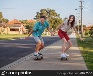 Happy brother and sister having fun with skateboard on the street in the evening light