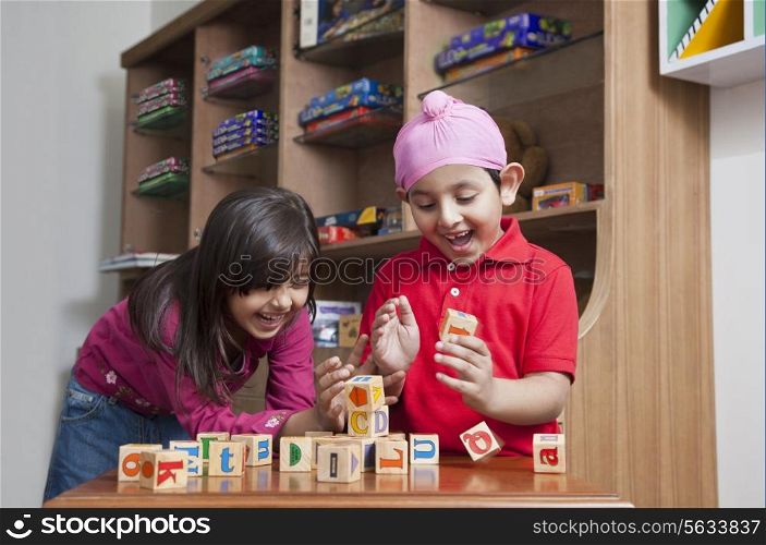 Happy brother and sister playing with wooden toy blocks