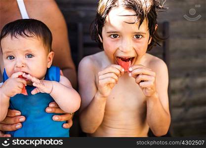 Happy brothers eating watermelon on summer day