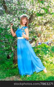 happy brunette posing near the tree at the time of flowering cherry