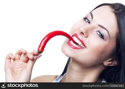 happy brunette woman biting chili pepper on white background