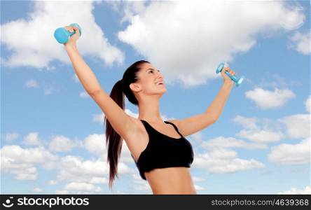 Happy brunette woman toning her muscles on a bluy sky of background
