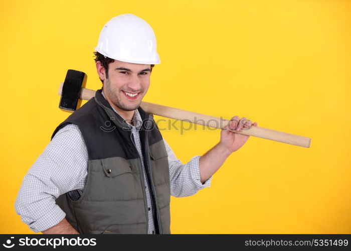 Happy builder carrying sledge-hammer