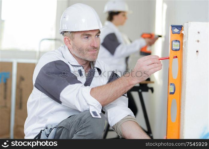 happy builder checking work with spirit level