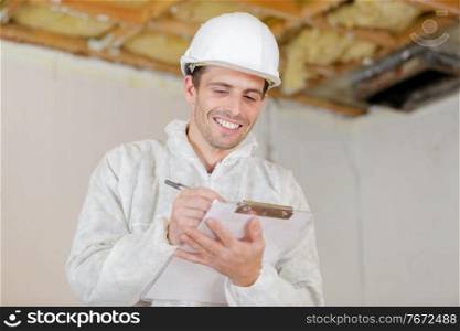 happy builder pointing finger and holding clipboard