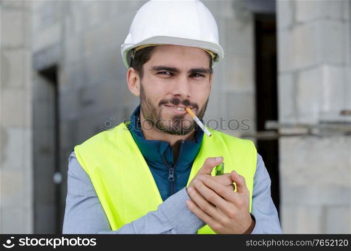 happy builder smoking cigarette on construction site