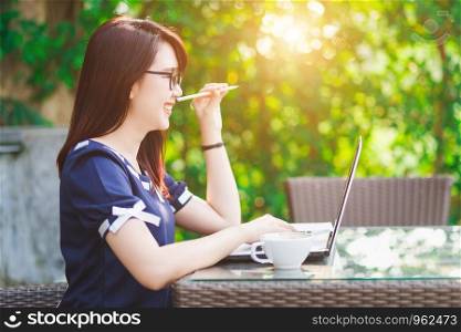 Happy Business Asian woman catch pencil working with laptop computer on office outdoor.