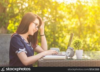 Happy business Asian woman working with laptop computer and clock,notebook on office outdoor.