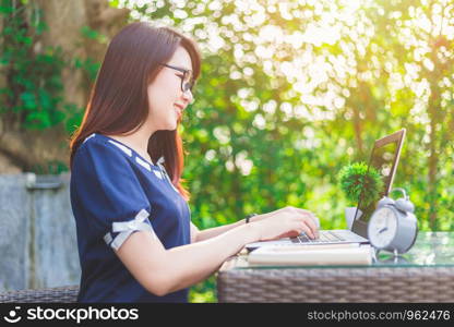 Happy business Asian woman working with laptop computer and clock,notebook on office outdoor.