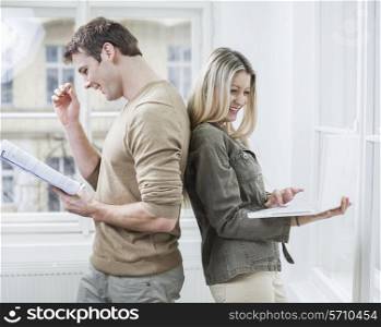 Happy business couple holding book and laptop in office