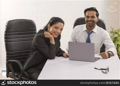 Happy business couple looking at camera with smile while working