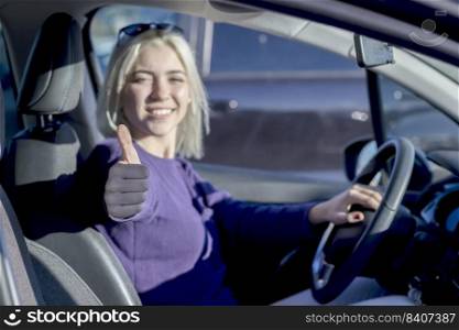 Happy business lady driving her car and showing thumb up.