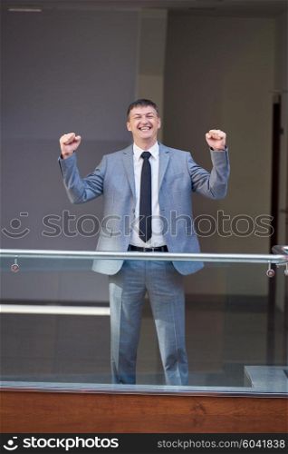 happy business man raise hands from joy at modern office