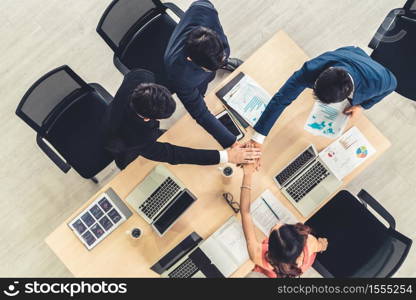 Happy business people celebrate teamwork success together with joy at office table shot from top view . Young businessman and businesswoman workers express cheerful victory showing unity and support .