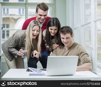 Happy business people using laptop in meeting