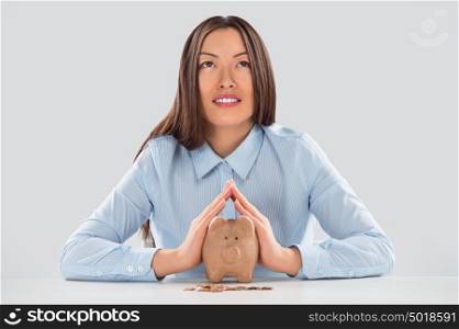 Happy business woman covering piggy bank with two hands - safety for your money concept