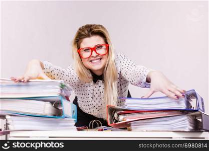 Happy business woman feeling energetic sitting working at desk full off documents in binders.. Happy business woman in office