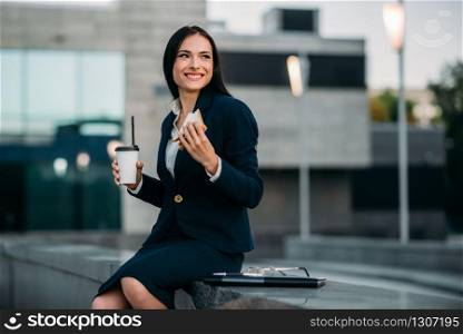 Happy business woman in suit have lunch outdoor. Modern building, financial center, cityscape. Female businessperson in suit at workplace