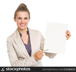 Happy business woman pointing with pen on blank paper sheet