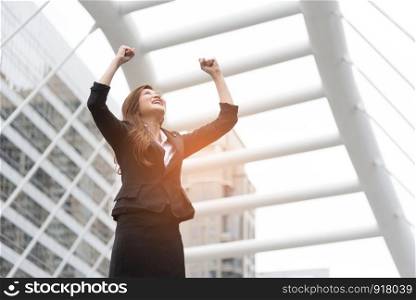 Happy business woman raise her hands at outdoors. Goal and successful concept. City and urban background
