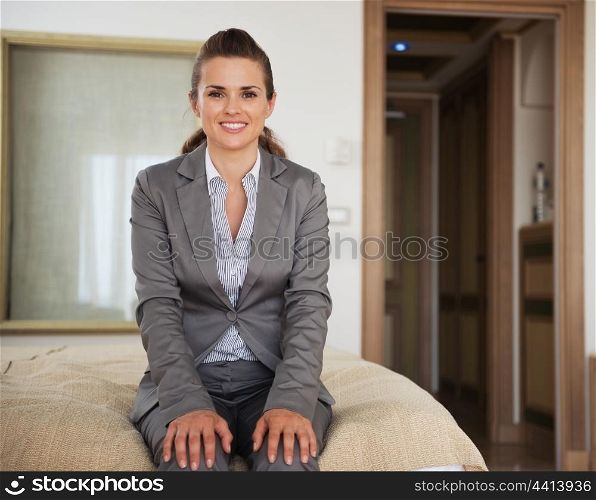 Happy business woman sitting on bed in hotel room
